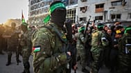 Hamas’ın askeri kanadına bağlı savaşçılar kalabalığı kontrol ederken, Kızılhaç 19 Ocak 2025’te Gazze Şehri’nde serbest bırakılacak İsrailli rehineleri teslim alırken.