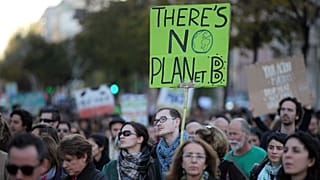 A young man carries a sign "There's no planet B" while taking part in a World Climate March in Lisbon, Sunday, Nov. 29 2015.