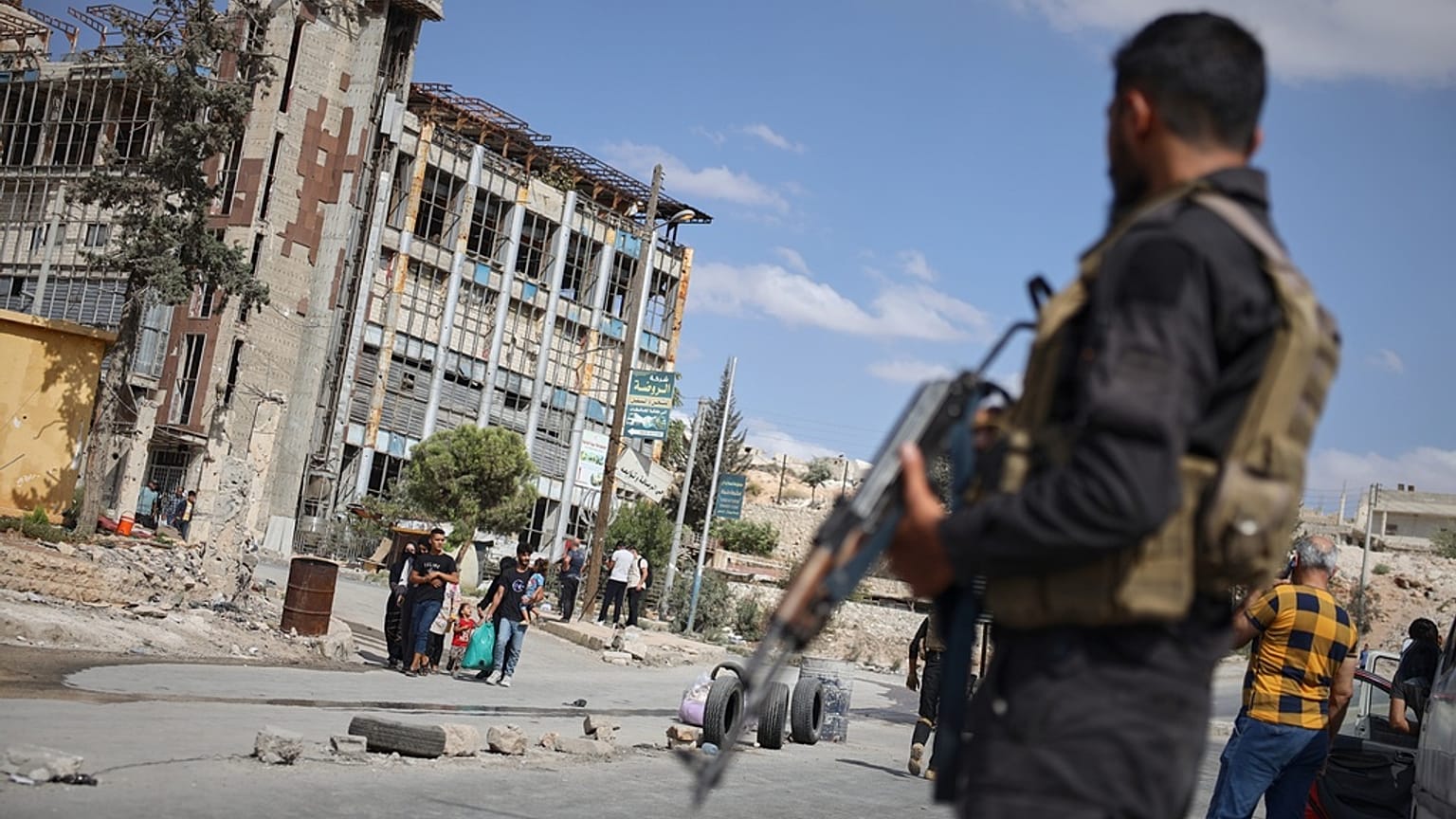 قوات الأمن السورية تقف في حراسة بينما يغادر السكان حيي الشيخ مقصود والأشرفية في حلب