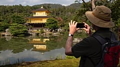 Un touriste prend une photo du célèbre temple Kinkakuji, souvent appelé Pavillon d'or, à Kyoto,