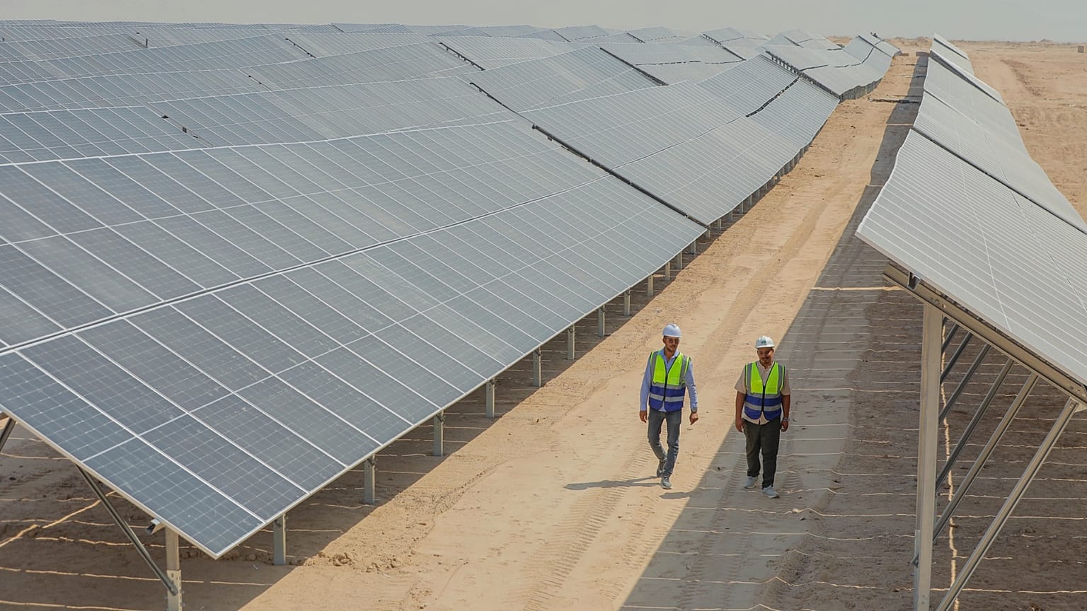 Workers walk between solar panels at a newly opened industrial-scale solar power plant in Karbala, Iraq, Wednesday, Sept. 17, 2025