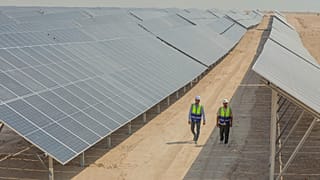 Workers walk between solar panels at a newly opened industrial-scale solar power plant in Karbala, Iraq, Wednesday, Sept. 17, 2025