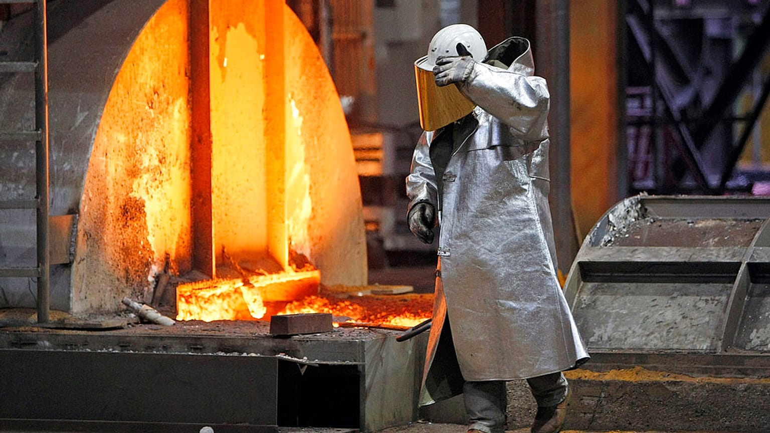 يحمي عامل نفسه من الفولاذ الساخن في فرن مصنع ثيسن كروب للصلب في دويسبورغ، ألمانيا