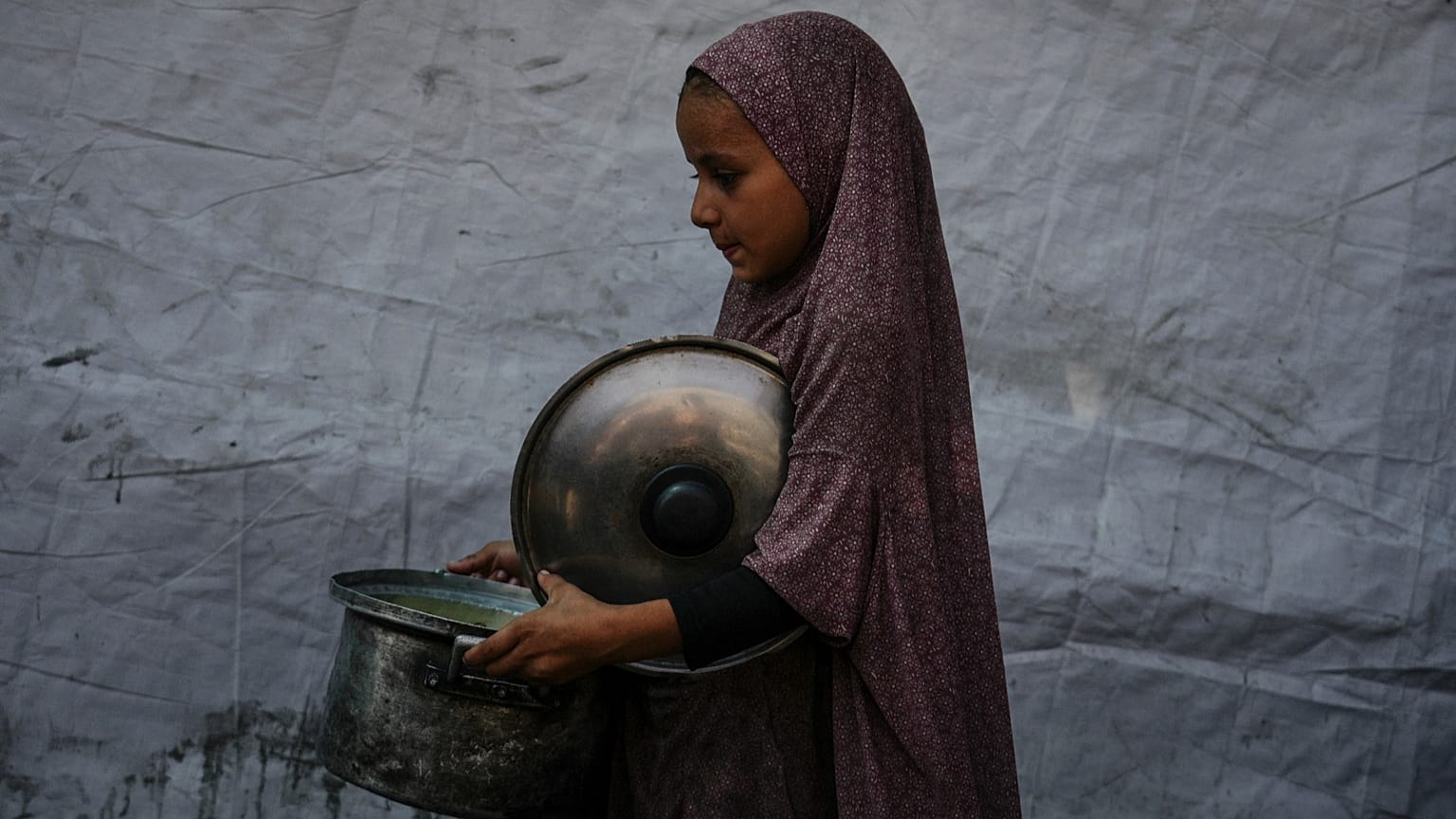 A Palestinian child carries a pot of donated food from a community kitchen in Deir al-Balah, southern Gaza Strip, on Sept. 6, 2025.