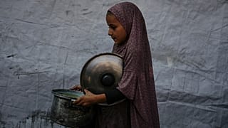 A Palestinian child carries a pot of donated food from a community kitchen in Deir al-Balah, southern Gaza Strip, on Sept. 6, 2025.