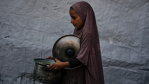 A Palestinian child carries a pot of donated food from a community kitchen in Deir al-Balah, southern Gaza Strip, on Sept. 6, 2025.