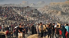 People carry humanitarian aid that was unloaded from a World Food Programme convoy in the northern Gaza Strip, 16 June, 2025