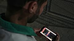 فلسطيني ينظر إلى هاتفه الذي يعرض صورة لترامب، بعد الإعلان عن اتفاق بين إسرائيل وحماس على المرحلة الأولى من خطة وقف القتال، الخميس 9 أكتوبر/تشرين الأول 2025. 