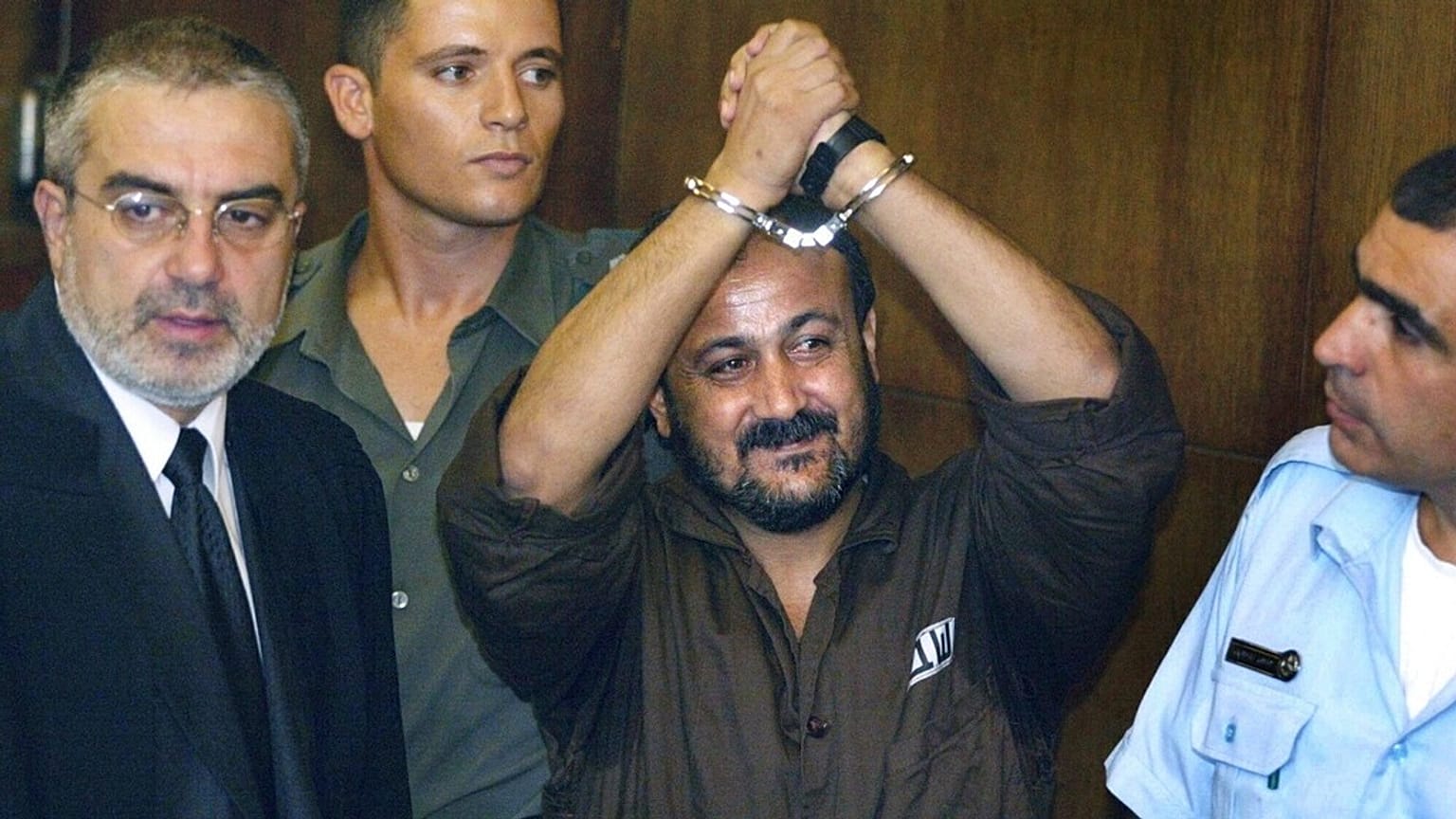 مروان البرغوثي يرفع يديه المكبلتين في اليوم الأول من محاكمته في تل أبيب، 14 أغسطس 2002.