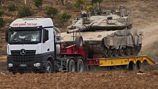 Грузовик вывозит танк израильской армии из сектора Газа