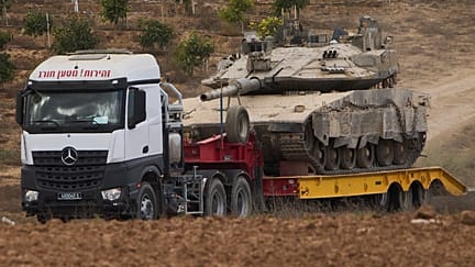 Грузовик вывозит танк израильской армии из сектора Газа