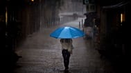 ARCHIVO - Una mujer camina bajo una intensa lluvia en Barcelona, ​​España, el jueves 11 de septiembre de 2025.