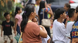 A woman hugs a child as parents and children evacuate a school after a strong earthquake in Davao City, Philippines, on Friday, Oct. 10, 2025