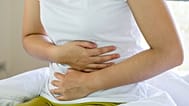 A woman clutches her abdomen.