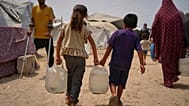 أطفال فلسطينيون ينقلون عبوات مياه تم جمعها من نقطة توزيع في مدينة غزة، 12 أغسطس/آب 2025