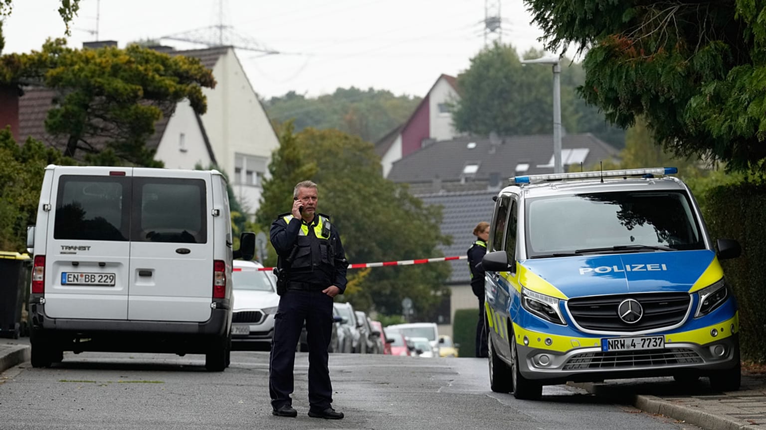 Ein Polizist telefoniert am 7. Oktober 2025, auf einer Straße in Herdecke, nachdem die neu gewählte Bürgermeisterin Iris Stalzer schwer verletzt  in ihrem Haus gefunden wurde.