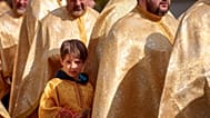 Ребенок рядом с румынскими православными священниками во время паломничества в Вербное воскресенье. Бухарест, Румыния, 12 апреля 2025 года. 