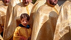 Ребенок рядом с румынскими православными священниками во время паломничества в Вербное воскресенье. Бухарест, Румыния, 12 апреля 2025 года. 