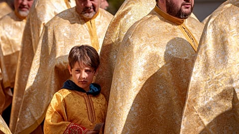 A child stands next to Romanian Orthodox priests during an Orthodox Palm Sunday pilgrimage in Bucharest, Romania, Saturday, April 12, 2025. (AP Photo/Andreea Alexandru)