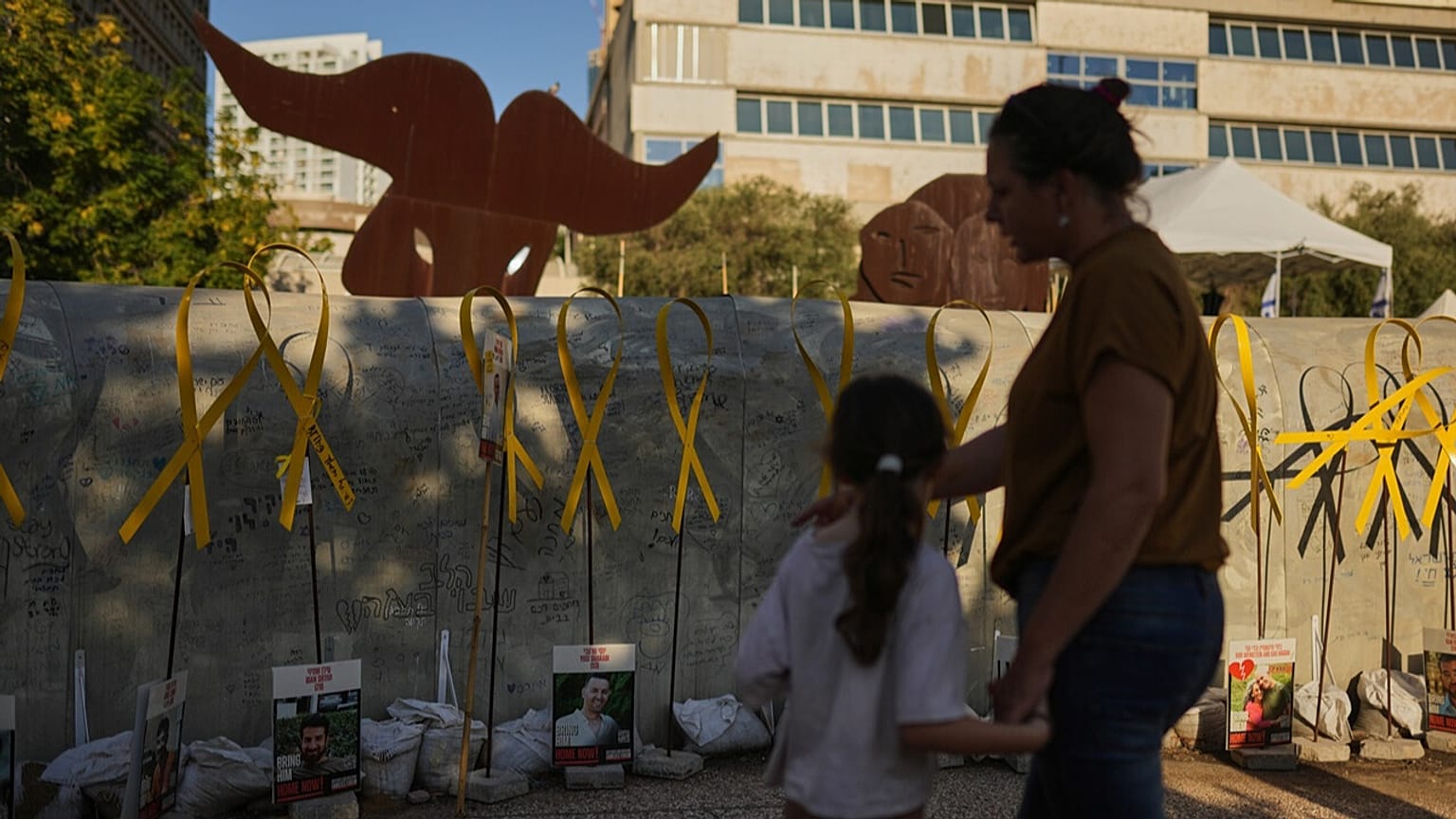 People walk past an installation simulating a tunnel in Gaza at a plaza known as hostages square, in Tel Aviv, Israel, Friday, Oct. 10, 2025.
