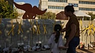 People walk past an installation simulating a tunnel in Gaza at a plaza known as hostages square, in Tel Aviv, Israel, Friday, Oct. 10, 2025.
