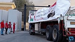 Des membres du Croissant Rouge égyptien surveillent des camions transportant de l'aide humanitaire à l'entrée du point de passage de Rafah, entre l'Égypte et la bande de Gaza. Dimanche 12 octobre 2025.