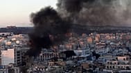 عمود من الدخان يتصاعد من مبانٍ خلال مواجهات بين محتجين والشرطة في العاصمة تونس، الجمعة 14 يناير 2011.