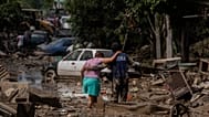 Un infante de marina ayuda a una mujer a cruzar una calle inundada en Poza Rica, Veracruz, México, el domingo 12 de octubre de 2025.
