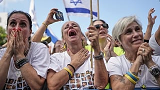 Les gens réagissent alors qu'ils se rassemblent pour regarder la retransmission en direct de la libération des otages israéliens à Gaza