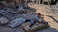 صبي فلسطيني مستلقٍ على فراش وسط ركام المباني المدمرة في خان يونس، جنوب قطاع غزة، يوم الجمعة 10 أكتوبر/تشرين الأول 2025،