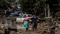 Um fuzileiro naval ajuda uma mulher a atravessar uma rua inundada em Poza Rica, Veracruz, México, no domingo, 12 de outubro de 2025
