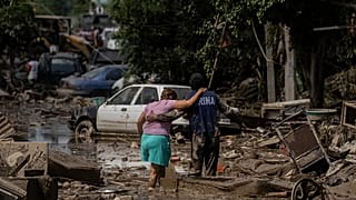Um fuzileiro naval ajuda uma mulher a atravessar uma rua inundada em Poza Rica, Veracruz, México, no domingo, 12 de outubro de 2025