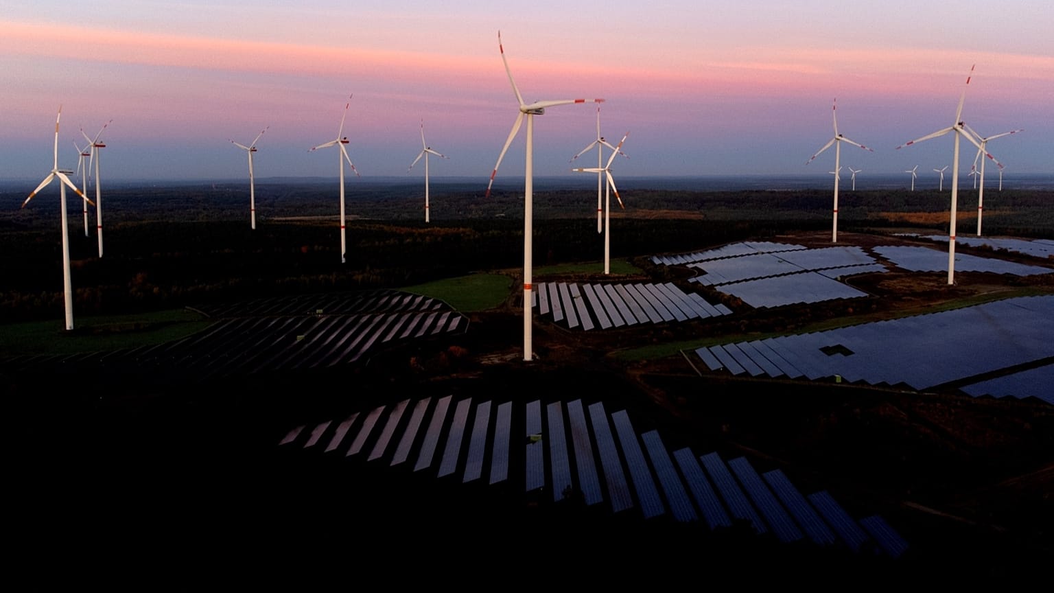 Wind turbines operate as the sun rises at the Klettwitz Nord solar energy park near Klettwitz, Germany, Oct. 16, 2024