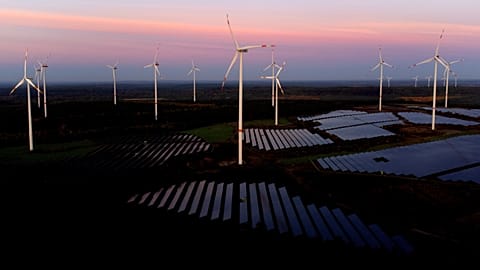 Wind turbines operate as the sun rises at the Klettwitz Nord solar energy park near Klettwitz, Germany, Oct. 16, 2024
