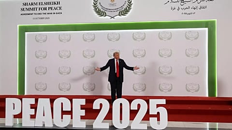 US President Donald Trump poses next to a sign at a world leaders' summit on ending the Gaza war in Sharm el-Sheikh, 13 October, 2025