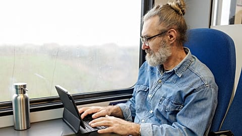 A man uses a tablet on the train.