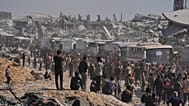 حافلات تقل أسرى فلسطينيين مفرجًا عنهم تمرّ قرب مبانٍ مدمّرة في خان يونس جنوب غزة، الإثنين 13 أكتوبر 2025.