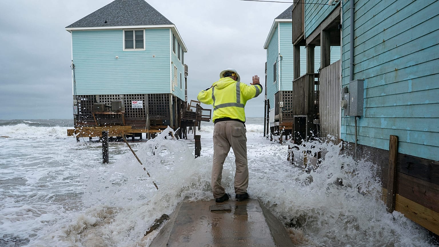 An electric company employee stands on a septic tank as he checks a home after a storm, Monday, Oct. 13, 2025, in Buxton, N.C. (AP Photo/Allison Joyce)