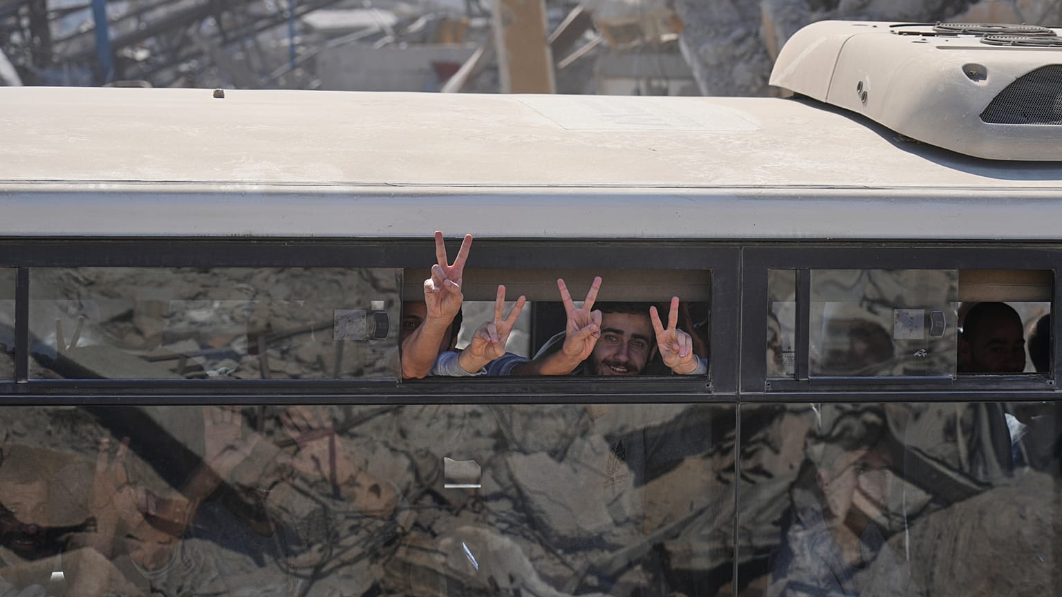 Prisioneros palestinos liberados en un autobús hacen el signo de la victoria