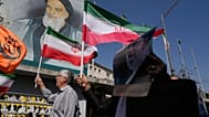 مصلّون إيرانيون يرفعون الأعلام الإيرانية وصورة للمرشد الأعلى آية الله علي خامنئي، إلى اليمين، أمام صورة مؤسس الثورة الراحل آية الله الخميني