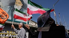 مصلّون إيرانيون يرفعون الأعلام الإيرانية وصورة للمرشد الأعلى آية الله علي خامنئي، إلى اليمين، أمام صورة مؤسس الثورة الراحل آية الله الخميني