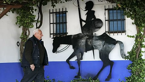 Un hombre camina junto a una figura de Don Quijote a caballo en la región de La Mancha, España, el 14 de enero de 2005.