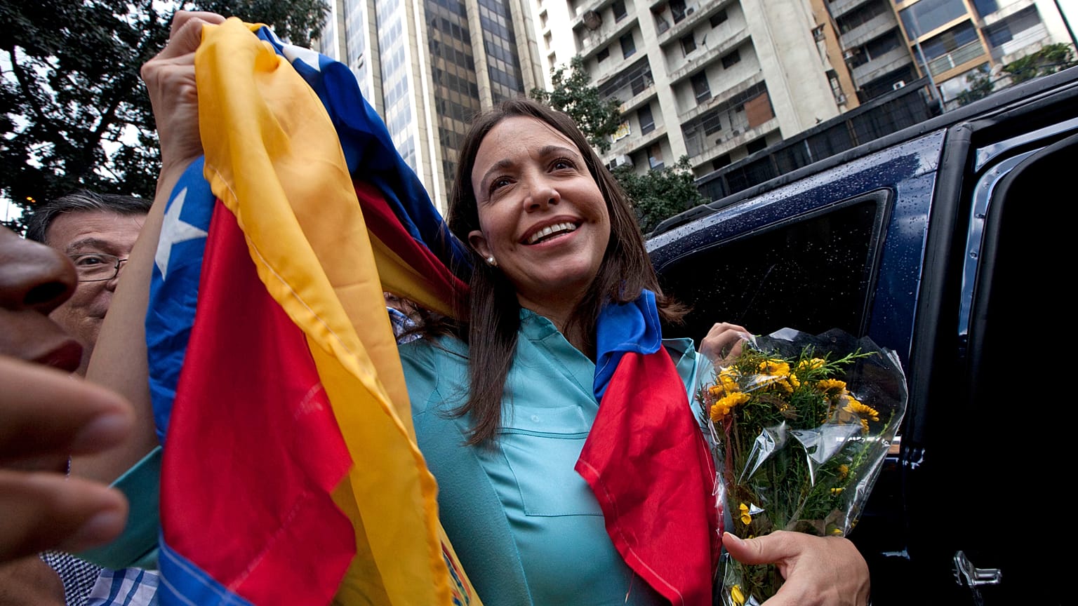 ARCHIVO - La ex congresista y líder de la oposición María Corina Machado sostiene la bandera venezolana afuera de la Fiscalía General de la República en Caracas, en 2014.