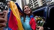 ARCHIVO - La ex congresista y líder de la oposición María Corina Machado sostiene la bandera venezolana afuera de la Fiscalía General de la República en Caracas, en 2014.