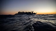 Migrants and refugees wait for assistance on an overcrowded wooden boat, as aid workers approach them in the Mediterranean Sea off the Libyan coast, 12 February 2021