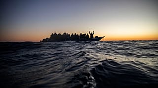 Migrants and refugees wait for assistance on an overcrowded wooden boat, as aid workers approach them in the Mediterranean Sea off the Libyan coast, 12 February 2021