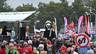 Manifestantes marcham com um esqueleto e faixas