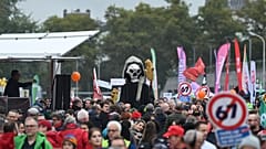 Protestierende marschieren mit einem Skelett und Bannern