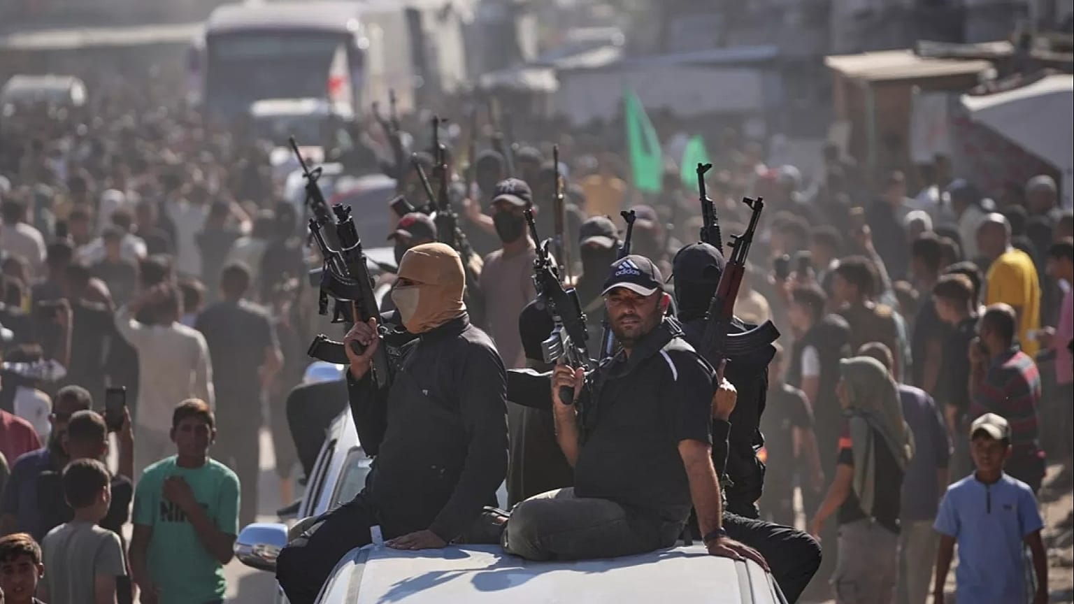  مسلحون من حماس على متن شاحنات صغيرة يرافقون حافلات تقل سجناء فلسطينيين محررين، خان يونس، جنوب قطاع غزة، الاثنين 13 أكتوبر/تشرين الأول 2025. 