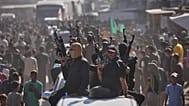  مسلحون من حماس على متن شاحنات صغيرة يرافقون حافلات تقل سجناء فلسطينيين محررين، خان يونس، جنوب قطاع غزة، الاثنين 13 أكتوبر/تشرين الأول 2025. 